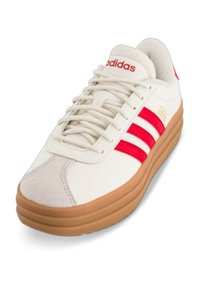 Sneaker Adidas con una toma in pelle bianca, accenti rossi e tre strisce. Presenta una suola in gomma e una collo imbottito per il comfort.