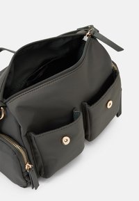 Borsa in nylon grigio con scomparto principale con zip, due tasche frontali con chiusure a scatto dorate e ferrature con cerniere tono oro.