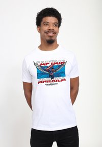 Camiseta de algodón blanca con una gran impresión gráfica de un superhéroe, texto rojo "CAPITÁN AMÉRICA" y elementos de fondo azules.