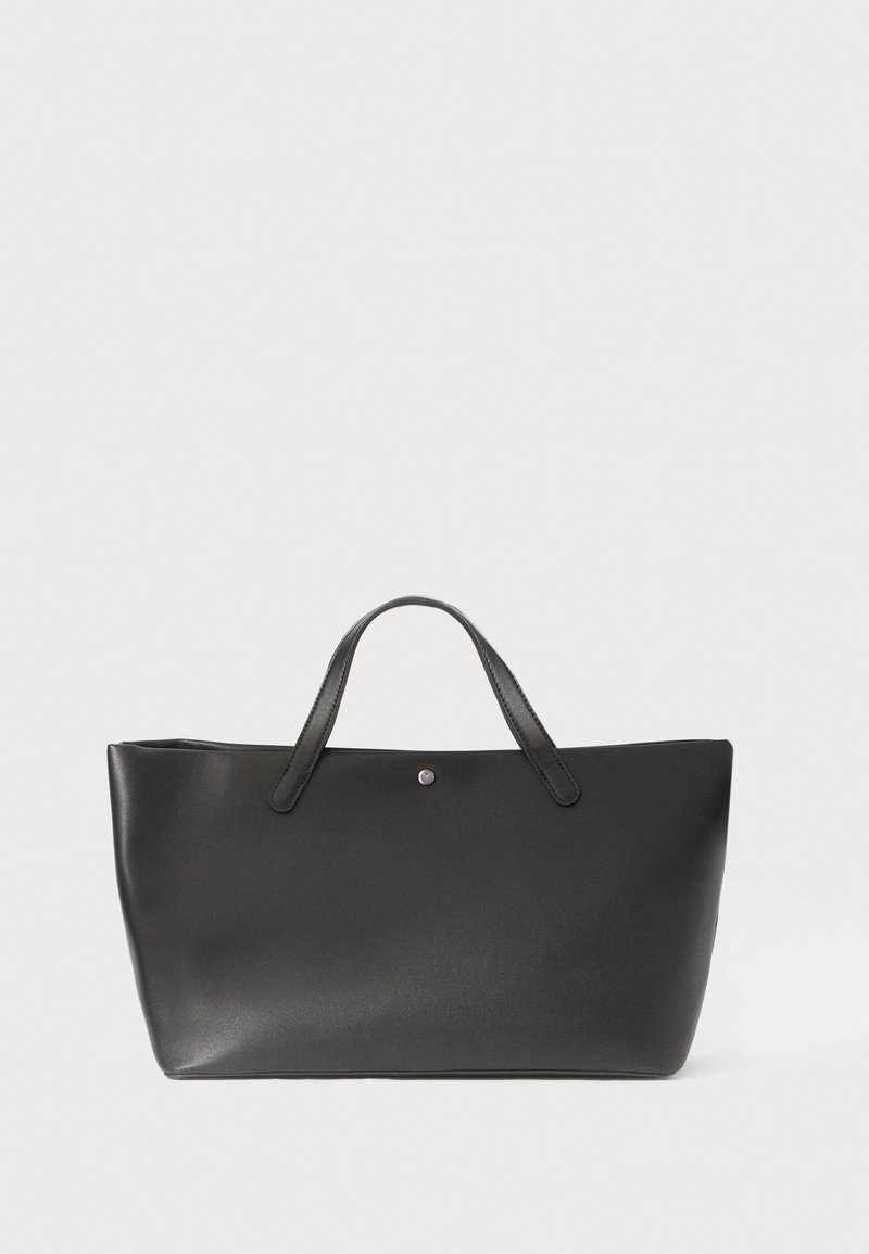 Black leather tote bag with two handles, minimalist design, smooth texture, featuring a small metal accent in the center front.