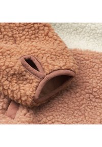 Veselă din fleece, realizată dintr-un material moale, texturat, de culoare maro, cu o margine netedă de culoare maro. Include o deschidere, plasată pe un fundal crem.
