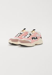 Une paire de baskets FILA rose, blanche et beige avec des semelles épaisses, un logo noir sur les côtés, des lacets blancs et des languettes de tirage noires sur la languette.