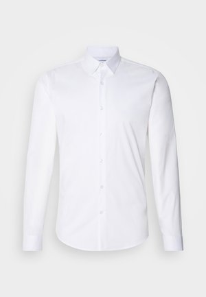 Biała koszula z długim rękawem zapinana na guziki, wykonana z gładkiej bawełnianej tkaniny, z klasycznym kołnierzykiem, zapięciem na guziki i zaokrąglonym dołem.