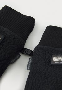 De sorte fleecehandsker i sort med ribbede manchetter, udstyret med en rem med spænde og mærker, der viser "Columbia" og "Rely on Warmth."