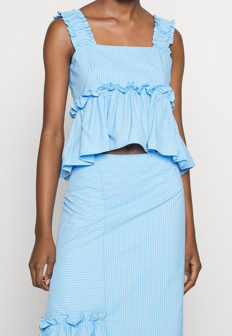 Ljust blå randig croppad topp med volangspännen och utsvängd nederkant, matchad med en passande åtsittande kjol med volangdetalj i nederkant.