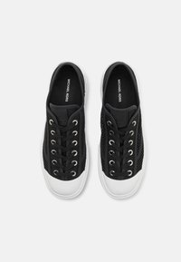 Svarte mesh-sneakers med hvite gummisåler, med sølv øyelet og snørebånd. Innvendig har de logo-merke i kontrastfarge.