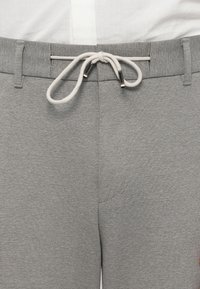 Γκρι αθλητικά σορτς με υφασμάτινη υφή, ρυθμιζόμενο κορδόνι με μεταλλικές άκρες και πλαϊνές τσέπες με ενισχυμένα ράμματα.