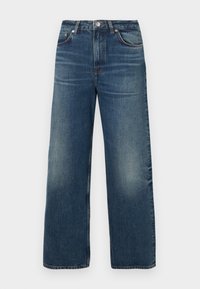 Jean denim bleu à jambes larges avec fermeture à boutons et zip à l'avant, poches avant et arrière, et décoloration sur les cuisses.