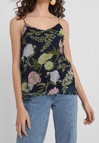 Kwiecowy top na ramiączkach w ciemnoniebieskim kolorze, z intensywnie różowymi i zielonymi kwiatami. Regulowane ramiączka spaghetti i luźny fason.
