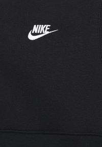 Sudadera negra con una textura suave, que presenta un logo de Nike bordado en blanco en la parte izquierda del pecho y un dobladillo acanalado.