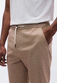 Μπεζ, ελαφριά σορτς από λινό με ελαστική μέση, ρυθμιζόμενο κορδόνι και πλαϊνές τσέπες· υφασμένο ύφασμα με casual εφαρμογή.