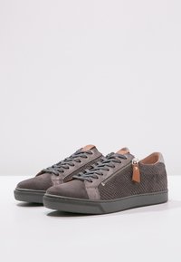 Graue Wildledersneaker mit strukturierten Seitenpanelen, runder Spitze, kontrastierenden, tanfarbenen Akzenten und dekorativem Reißverschlussdetail an der Außenseite.