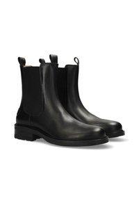 Botas Chelsea de cuero negro con paneles laterales elásticos, puntera redonda y lengüetas. Presentan una suela de goma texturizada y duradera.