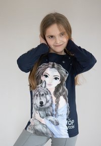 Maglietta a maniche lunghe blu navy con un design stampato di una ragazza con i capelli lunghi e un lupo, accentuato da stelle e dal testo "TOP Model."