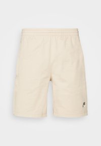 Beige Nike shorts with an elastic waistband, side pockets, and a small black logo on the lower right leg. Smooth, lightweight fabric.