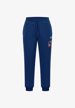 Pantalons de jogging bleu marine en tissu doux, avec une taille élastique, des chevilles resserrées et une patch avec un numéro sur le côté.