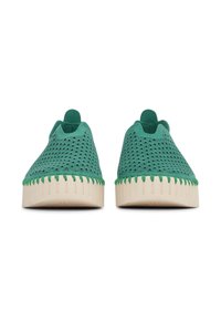 Para zielonych butów wsuwanych z falistymi perforacjami i beżowymi gumowymi podeszwami, pokazanych z przodu na białym tle.