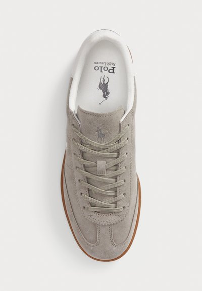 Sneaker in suede di un grigio chiaro con colletto imbottito bianco e suola in gomma beige. Presentano lacci in tonalità abbinata e un piccolo logo vicino alla linguetta.