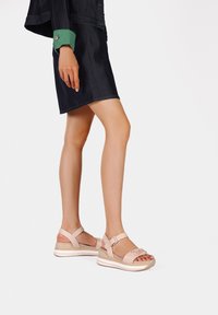 Sandali rosa chiaro con cinturino alla caviglia regolabile, tomaia texturizzata, suola piattaforma bianca chunky e discreto dettaglio del logo nella parte anteriore.