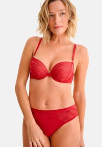 Ensemble bikini rouge comprenant un soutien-gorge rembourré avec des armatures et des détails à lignes verticales, assorti à une culotte taille haute avec des accents de tissu contrastants.