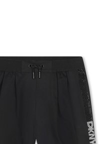 Pantalons de jogging noirs avec une taille à cordon de serrage, présentant un accent brillant de strass sur le côté et un détail textuel en blanc.