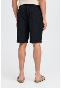 Black, knee-length shorts with a rolled hem, elastic waistband, and a single back pocket, made from lightweight fabric.