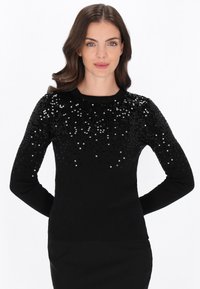 Fekete pulóver lekerekített nyakkivágással, az upper felén fényes fekete és ezüst flitterek színátmenetével, az ujjakon bordázott textúrával.