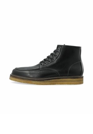 Botín de cuero negro hasta el tobillo con punta redonda, seis ojales metálicos para los cordones, costuras en contraste y suela de goma texturizada.