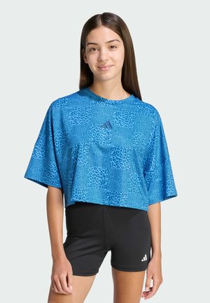 Blue cropped t-shirt featuring a leopard print pattern, short sleeves, and an Adidas logo in the center. Paired with black shorts.