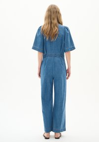 Jeansoverall mit kurzen, weiten Ärmeln, tailliertem Schnitt und weitem Hosenbein. Blaustoff mit sichtbaren Stichdetails.