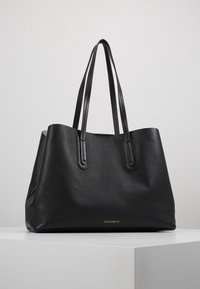 Sort læder tote taske med en tekstureret overflade, to lange håndtag, åben top og et guldlogo i bunden. Enkelt, rummeligt design.