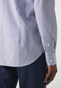 Camicia a righe blu e bianche con maniche lunghe, polsini con bottoni, orlo curvo e tessuto di cotone liscio.