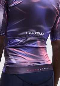 Άτομο που φοράει ποδηλατική φανέλα με διαβάθμιση από μωβ σε ροζ, με λογότυπα "CASTELLI" και "ROSSO CORSA" στην πλάτη.
