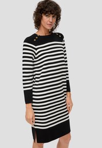 Schwarz-weißer gestreifter Kleid mit langen Ärmeln, seitlichen Schlitzen und goldenen Knopfakzenten an den Schultern. Strickstoff, lässige Passform.