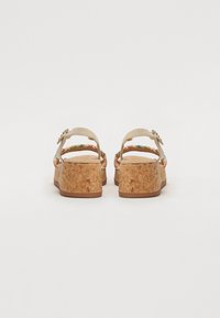 Sandales en liège à talon compensé avec une sangle beige et des accents tressés colorés, dotées d'une boucle réglable et d'une semelle texturée pour une meilleure adhérence.