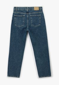 Jeans de denim en un lavado azul medio, con un corte relajado, dos bolsillos traseros, una parche de cuero marrón en la cintura, y un diseño de pierna recta.