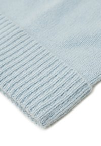 Lichtblauwe gebreide trui met geribbelde structuur aan de zoom. Zachte, donzige uitstraling die de delicate stiksels en gelijkmatigheid benadrukt.