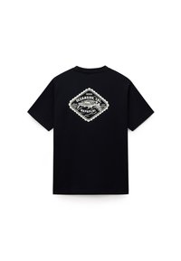 Černé tričko s krátkým rukávem s bílým diamantovým grafickým motivem na zádech, na kterém je nápis "Oceanside, Cal," "1987" a ilustrace budovy.