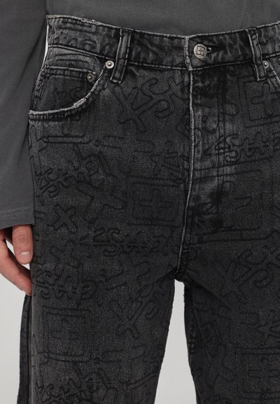 Jeans negre din denim cu un model texturat de desene abstracte, cinci buzunare și un sistem de închidere cu buton metalic la talie.