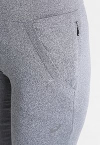 Graue Sportleggins aus einem strukturierten, melierten Stoff. Verfügt über eine seitliche Reißverschlusstasche und ein kleines Logo-Detail. Enganliegendes Design.