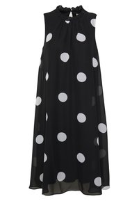 Svart ärmlös klänning med vita prickar, med en volangkrage och ett flödande, lätt tyg.