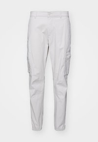 Pantalones cargo de color gris claro, hechos de una tela ligera, con un corte recto, puños elásticos y bolsillos laterales con cremalleras.