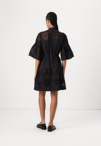 Must mustrips sundress, mille radikaalne lõike ning detailidega varrukatel ja äärel. Üksildne kangas koos rõhutatud talje detailiga.