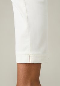 Vita beskurna byxor med en ren avslutning i fållen. Tyget verkar slätt med en lätt lyster. Har en skräddarsydd passform.