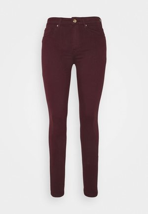 Burgundy skinny jeans made from stretchy material, featuring a zip and button closure, five pockets, and a smooth texture.
