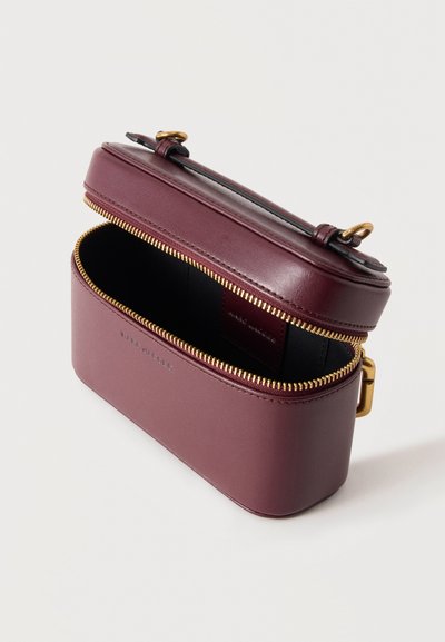 Petit sac bandoulière rectangulaire en cuir violet avec fermeture éclair dorée partiellement ouverte, intérieur noir et sangle ajustable sur fond blanc.