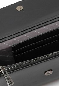 Portafoglio in pelle nera con una texture liscia, dotato di più scomparti per carte, un comparto con zip e una fodera in tessuto a strisce grigie.