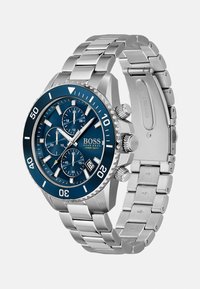Montre en acier inoxydable argenté avec un cadran bleu, fonctions chronographe et lunette rotative. Présente des index des heures audacieux et un affichage de la date.