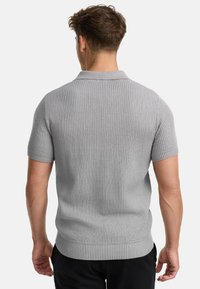 Graues, geripptes kurzärmliges Poloshirt mit flachem Kragen und strukturiertem Stoff, passgenauer Silhouette und kontrastierendem Saum.