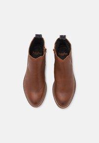 Botas de tobillo de cuero marrón con un acabado texturizado, punta afilada y paneles laterales elásticos. Incluyen una suela cosida y un forro negro.